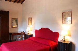 a bedroom with a red bed and two lamps at Locanda di Praticino in Rufina