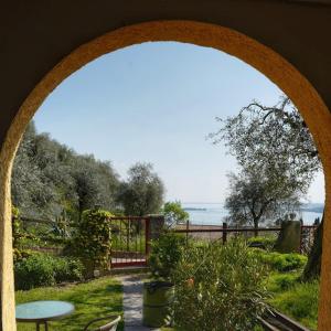 einen Torbogen, der zu einem Garten mit Meerblick führt in der Unterkunft Apartment Fasano Sopra in Gardone Riviera