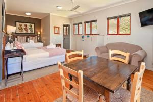 a bedroom with a bed and a dining room with a table at Baleens Hotel in Hermanus