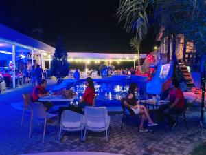 a group of people sitting at tables by a pool at night at Estrella Del Mar in Toledo City