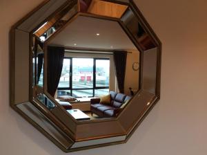 a mirror reflecting a living room with a couch at BORD DE L’EAU APARTMENT in Wick