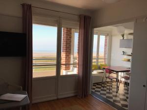 een kamer met een tafel en uitzicht op de oceaan bij Le Continental in Cayeux-sur-Mer