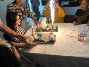 a group of people standing around a table with a birthday cake at Appartements in Basel - Leymen in Leymen