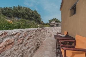 a table and chairs next to a stone wall at La Casa Di Nonna in Koríthion