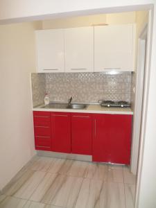 uma cozinha com armários vermelhos e um lavatório em Hotel Dioni em Paralia Katerinis