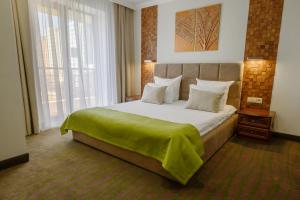 Un dormitorio con una cama grande con una manta verde. en Platan Yuzhniy Hotel en Krasnodar