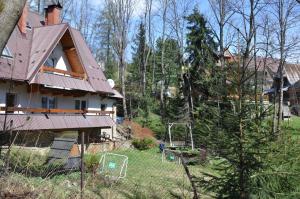 ein Haus mit einem Metalldach im Hof in der Unterkunft APARTAMENTY SOBICZKOWA WYSPA in Kościelisko