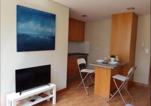 a living room with a television and a table with chairs at Cosy Santa Catarina Flat in Porto