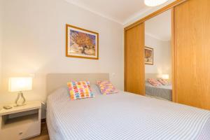 a small bedroom with a bed and a mirror at Buganvília By Algartur in Tavira