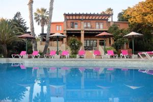 a pool with chairs and umbrellas in front of a house at Quinta do Mar - Country & Sea Village in Luz