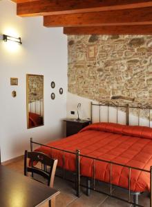 sypialnia z czerwonym łóżkiem i kamienną ścianą w obiekcie Antica Interamnia w mieście Teramo