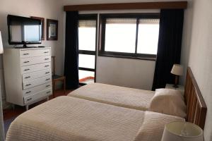 a bedroom with two beds and a dresser with a television at Residencial do Mar in Praia de Mira