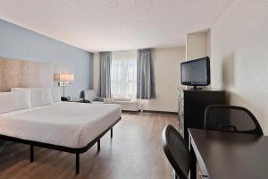 a hotel room with a bed and a flat screen tv at Extended Stay America Select Suites - Charlotte - Tyvola Rd in Charlotte