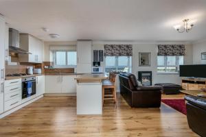 an open kitchen and living room with white cabinets at Arran View - Donnini Apartments in Ayr