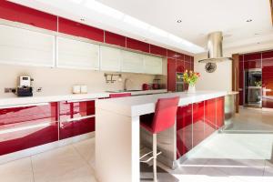 una cocina con armarios rojos y blancos y una silla roja en Modern Elegance, steps from the Aviva! Home Cinema, en Dublín