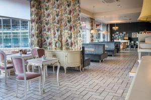 a restaurant with tables and chairs and a floral curtain at Meguva Resort Hotel in Palanga