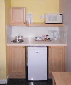 a small kitchen with a sink and a white refrigerator at Marlborough House - Guest House in Oxford +40 photos