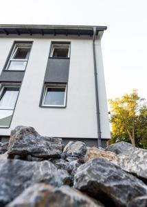 a white building with windows and rocks in front of it at Haus am Park - Ihr Gästehaus in Velbert in Velbert