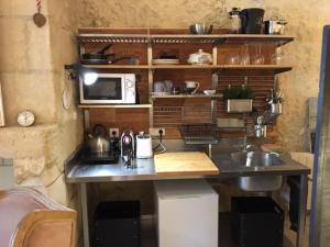 a kitchen with a counter with a sink and a microwave at Troglodytes "Loire Sauvage" (SPA) in Rochecorbon
