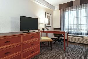 a hotel room with a desk and a flat screen tv at La Quinta Inn & Suites by Wyndham Ontario Airport in Ontario