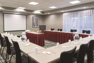 a conference room with tables and chairs and a screen at La Quinta Inn & Suites by Wyndham Ontario Airport in Ontario
