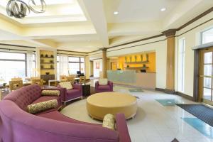 a lobby with purple chairs and a table and a kitchen at La Quinta by Wyndham Raleigh/Durham Southpoint in Durham