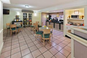 a restaurant with tables and chairs and a kitchen at La Quinta Inn by Wyndham Austin Oltorf in Austin