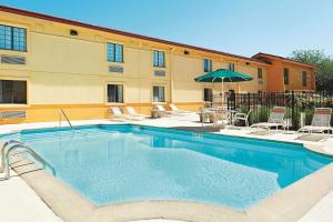 una gran piscina con sillas y sombrilla en La Quinta Inn by Wyndham Champaign, en Champaign