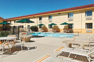 eine Hotelterrasse mit Tischen, Stühlen und einem Pool in der Unterkunft La Quinta Inn by Wyndham Champaign in Champaign