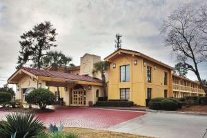 ein großes gelbes Gebäude mit einer roten Einfahrt in der Unterkunft La Quinta Inn by Wyndham Savannah Midtown in Savannah