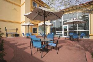 un patio con sillas, mesas y sombrillas en La Quinta by Wyndham Gallup, en Gallup