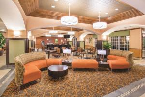 a lobby with orange furniture and tables and chairs at La Quinta by Wyndham Bentonville in Bentonville