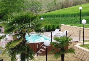 a swimming pool with a palm tree next to it at Bed And Breakfast Olimpia in San Salvatore Monferrato