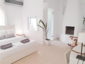 a white bedroom with a white couch and a fireplace at Thomas Apartments Katapola - Chora in Katapola