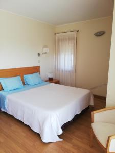 a bedroom with a large white bed and a chair at Moradia São Pedro in Porto Santo