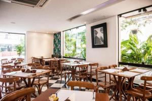 a restaurant with tables and chairs and large windows at Matiz Manhattan Hotel in São Paulo