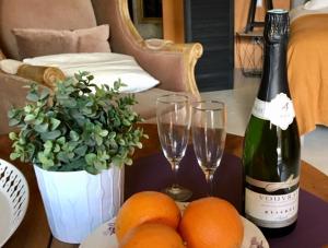 una bottiglia di vino, due bicchieri e delle arance su un tavolo di Troglodytes "Loire Sauvage" a Rochecorbon