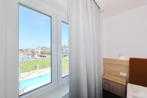 a bedroom with a window with a view of a pool at Hotel Mediteran in Zadar