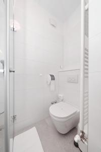 a white bathroom with a toilet and a shower at Hotel Mediteran in Zadar