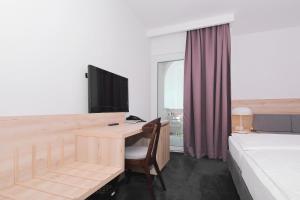 a bedroom with a desk and a bed and a desk with a computer at Hotel Mediteran in Zadar