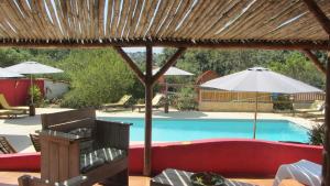 a pool with a red couch and an umbrella at Quinta das Cantigas by Book YourHoliday PT in Aljubarrota
