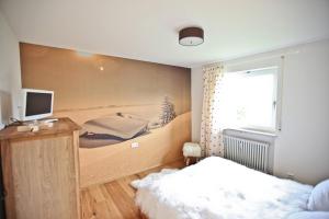 a bedroom with a bed and a desk with a television at Chaletwohnung Seeblick - Sauna und Dogfriendly in Oy-Mittelberg +19 photos