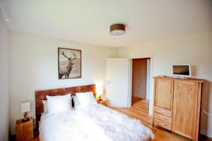 a bedroom with a bed and a dresser with a deer picture at Chaletwohnung Seeblick - Sauna und Dogfriendly in Oy-Mittelberg