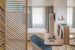 a hotel room with a bed and a desk with a laptop at OKKO Hotels Paris Gare de l'Est in Paris