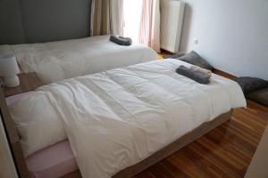 a bedroom with two beds with white sheets and a window at Comfy Apartment With Acropolis View in Athens