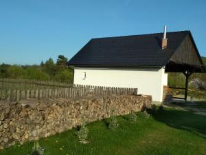 uma casa branca com uma parede de pedra e uma cerca em Rychlebská Pohoda em Černá Voda