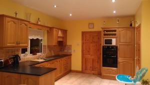 una cucina con armadi in legno e piano di lavoro nero di Warm and welcoming family home a Ballinrobe
