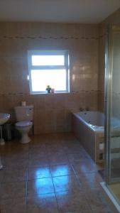 a bathroom with a tub and a toilet and a window at Warm and welcoming family home in Ballinrobe
