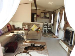 a living room with a couch and a tv at THE MONARCH LODGE ,Aviemore Holiday Park in Aviemore