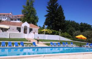 uma pessoa ao lado de uma piscina com cadeiras e guarda-sis em Hotel Urgeirica em Nelas